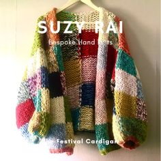 a colorful sweater hanging up on a wall with the words suzy rai written in white