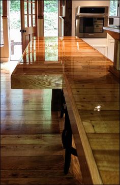 a kitchen with wooden floors and an island in the middle is seen from across the room