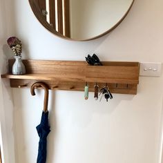 an umbrella is hanging on the wall next to a mirror and coat rack with keys