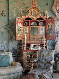 an old dresser and chair in a room with wallpapered walls, furniture and paintings on the walls