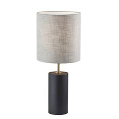 a black and gold lamp with a white shade on the top, sitting in front of a