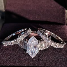 three wedding rings on top of each other with an engagement ring in the middle and diamond bands around them