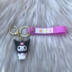 a keychain with a cat on it sitting on a furry surface next to a toy