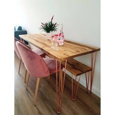 a wooden table topped with pink chairs next to a plant