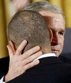 a man in a suit and tie hugging another man's head at a ceremony