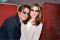 a man and woman sitting next to each other in front of a red chair with sunglasses on