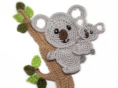 a crocheted koala bear sitting on top of a tree branch with leaves