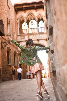 a woman is walking down the street with her arms spread out in front of her