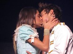 a man and woman kissing each other on stage