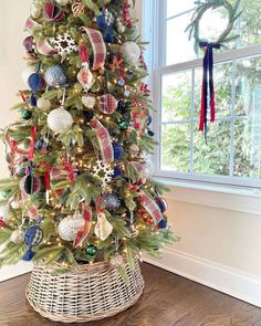 a decorated christmas tree with red, white and blue ornaments in a wicker basket