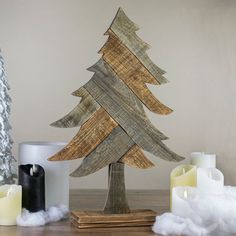 a wooden christmas tree sitting on top of a table next to candles and other decorations