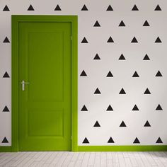 an open green door in front of a wall with black and white triangles on it