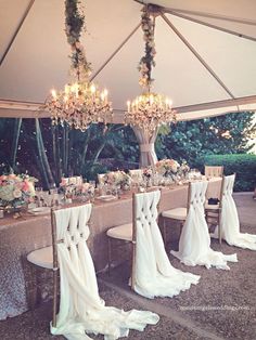 a long table with white chairs and chandeliers