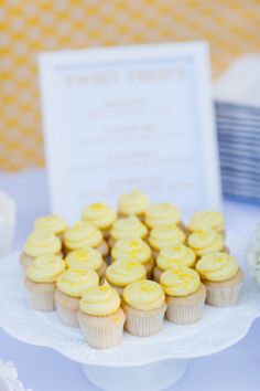 cupcakes are arranged on a cake plate with a sign in the background that says,