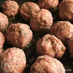 meatballs are cooking in a skillet with some sauce on the side and green herbs sprinkled on top