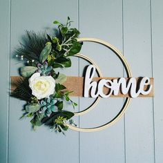 a wreath with flowers and greenery hanging on the wall