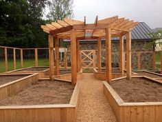 an outdoor garden area with raised beds and wooden pergolated structures on the ground