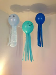 some balloons are hanging from the ceiling and one is blue with an octopus face on it