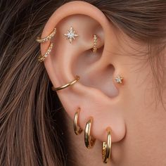 a woman wearing three different types of ear piercings