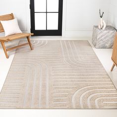 a beige rug with an abstract design on the floor in front of a chair and window