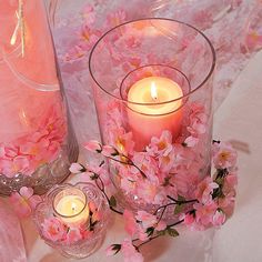 some pink flowers and candles on a table