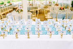 the table is set with place cards and gold figurines for guests to sign