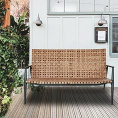 a bench sitting on top of a wooden floor next to a white wall and green plants