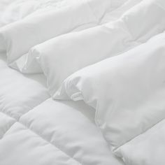 an unmade bed with white sheets and pillows