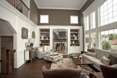 a living room filled with lots of furniture next to tall white walls and large windows