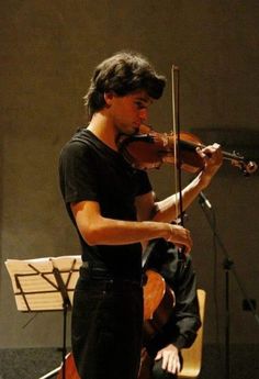 a young man playing the violin in front of an orchestra