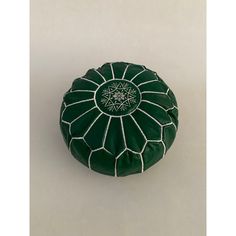 a green and white round poufce with an intricate design on the top, sitting on a plain surface