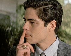 a man in a suit is holding his finger to his nose