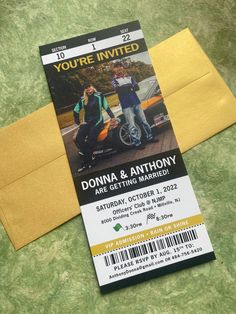 a ticket for an event with two men standing next to each other in front of a yellow envelope