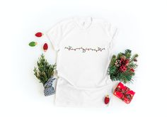 "Illuminate your festive wardrobe with our exquisite \"Christmas Light T-shirt.\" Hand-embroidered with intricate detailing, this tee showcases the magical essence of holiday lights. Features: Crafted from premium-quality cotton fabric. Soft and comfortable for all-day wear. Unique embroidered Christmas lights design. Tailored for a relaxed fit. Resilient and maintains embroidery vibrancy after multiple washes. This t-shirt isn't just a garment; it's a piece of wearable art, reflecting the festive charm of the holiday season. Whether you're attending a Christmas party or enjoying a winter evening stroll, this tee ensures you shine bright. A beautiful gift idea for friends, family, or yourself! Care Instructions: Machine wash cold. Turn garment inside out before washing. Lay flat to dry. Av Christmas White Embroidered Tops, Embroidered Christmas Holiday Tops, Holiday Embroidered Tops As Gift, White Festive Holiday T-shirt, Festive White Crew Neck T-shirt, White Crew Neck T-shirt For Festive Occasions, Winter Tees, Lights Design, Embroidered Christmas