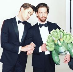 two men in tuxedos are holding some vegetables