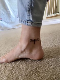 a woman's foot with a small dragonfly tattoo on the side of her ankle