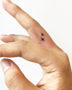 a person's hand with a tiny black star tattoo on the middle ring finger