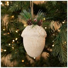 a white ornament hanging from a christmas tree with pine cones on the top