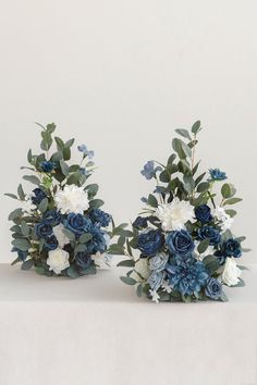 two blue and white bouquets sitting on top of a table next to each other