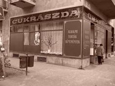 a black and white photo of a man standing in front of a store on the sidewalk