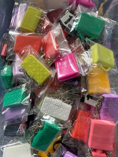 many different colored purses are on display in plastic bags with chains attached to them