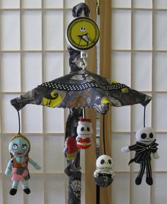 a wind chime with five creepy dolls hanging from it's sides and an umbrella in the middle