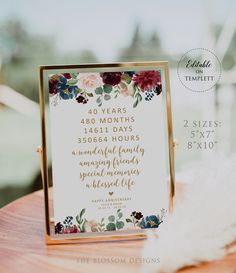 a sign with flowers on it sitting on top of a wooden table next to feathers