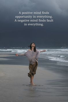 a woman standing on top of a beach next to the ocean with her arms outstretched