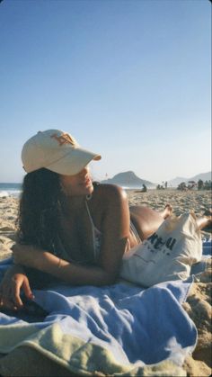 a woman laying on top of a beach next to the ocean