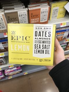 a person holding up a box of lemon tea in front of a store shelf filled with books