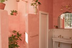 a bathroom with pink walls and plants on the wall