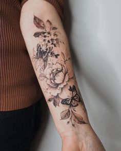 a woman's arm with flowers and butterflies tattooed on the left side of her arm