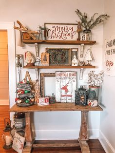 a wooden table topped with shelves filled with christmas decorations and other holiday related items in front of a white wall