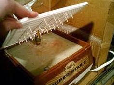 a person holding a toothbrush in front of a box with nails sticking out of it